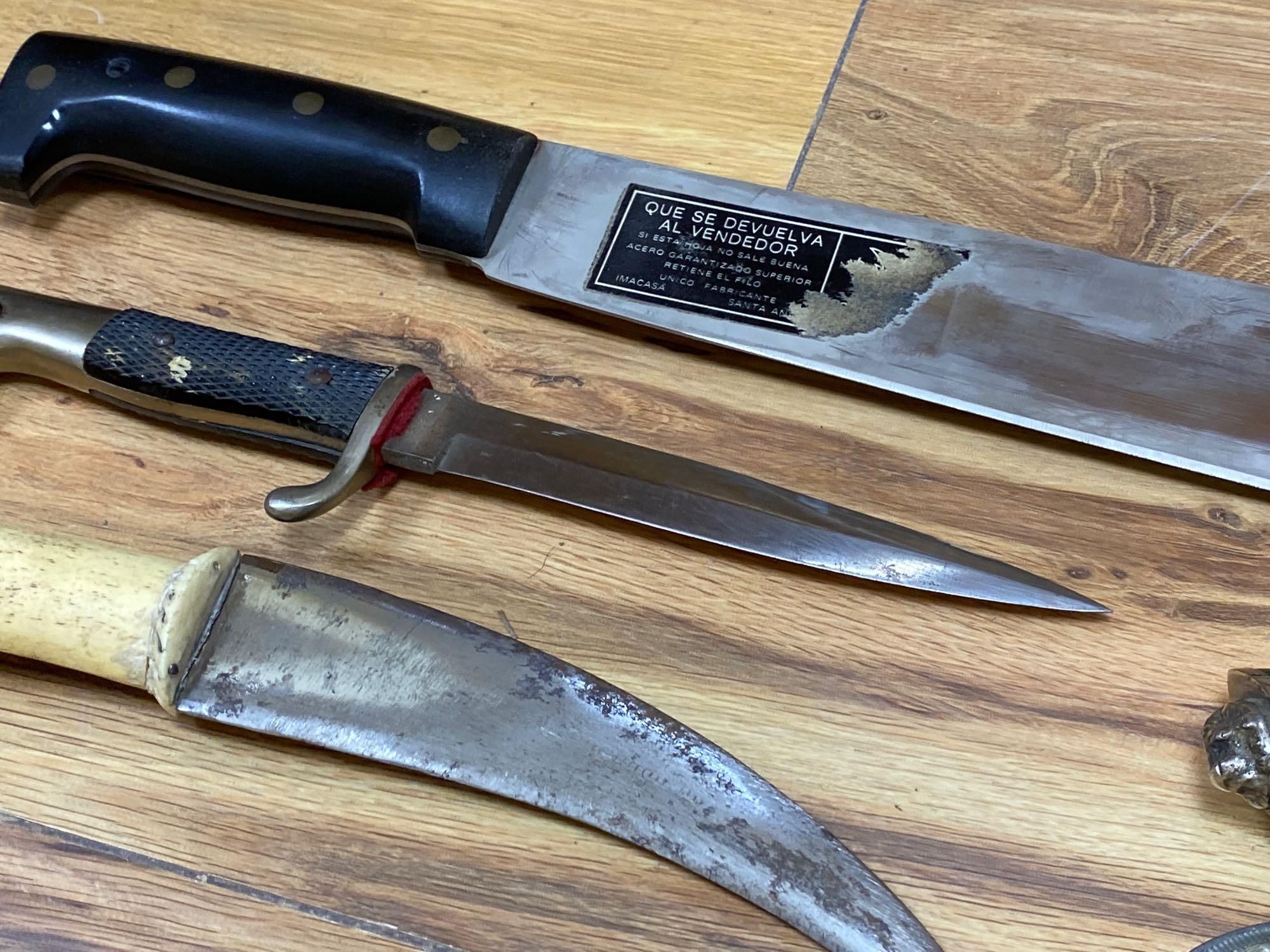 Five various weapons including a Kukri, a carved bone handled dagger with brass sun, moon and stars sheath and an El Salvador machete